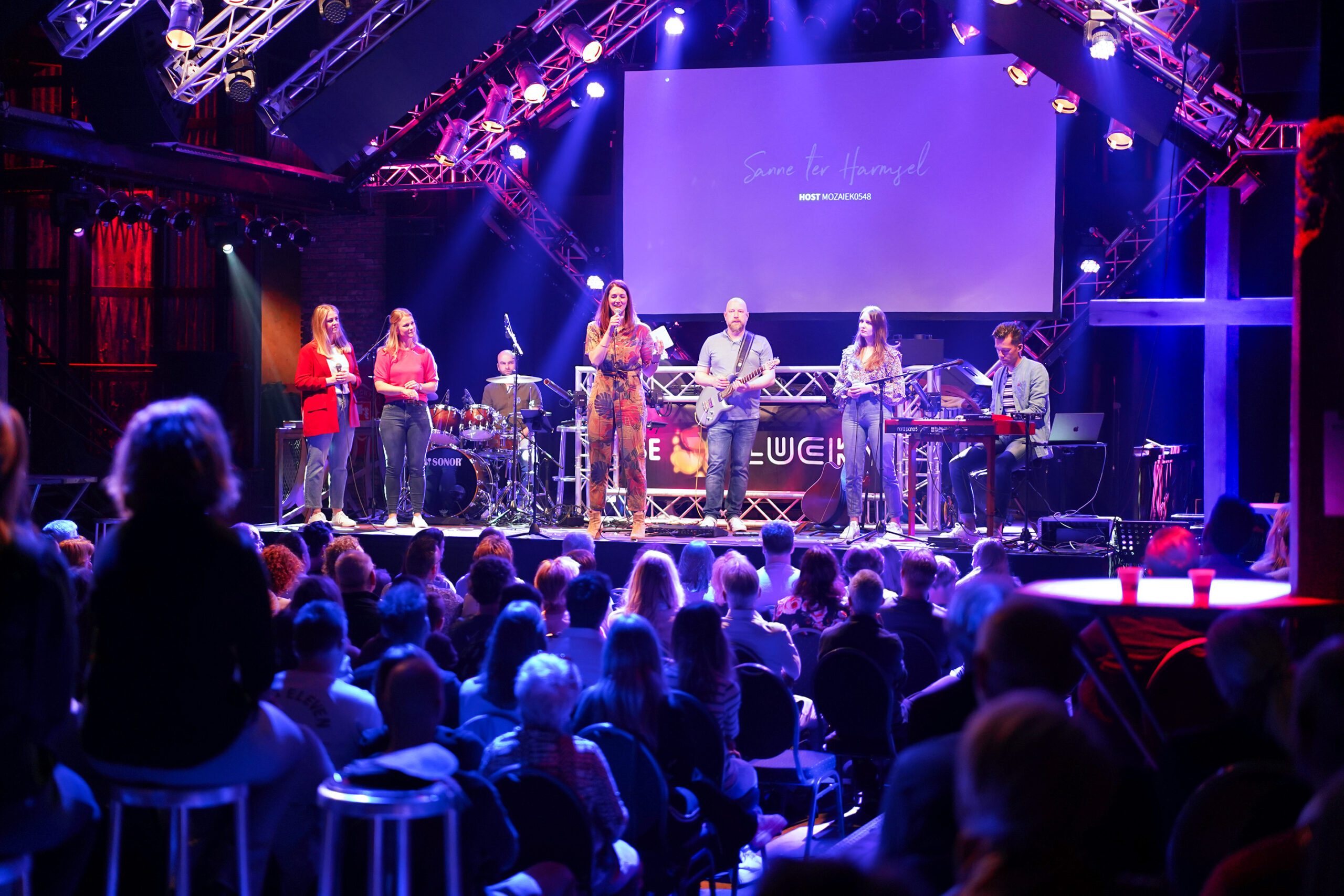 Worshipband speelt op het podium in Lucky terwijl de zaal vol bezoekers zit tijdens een dienst van Mozaiek0548