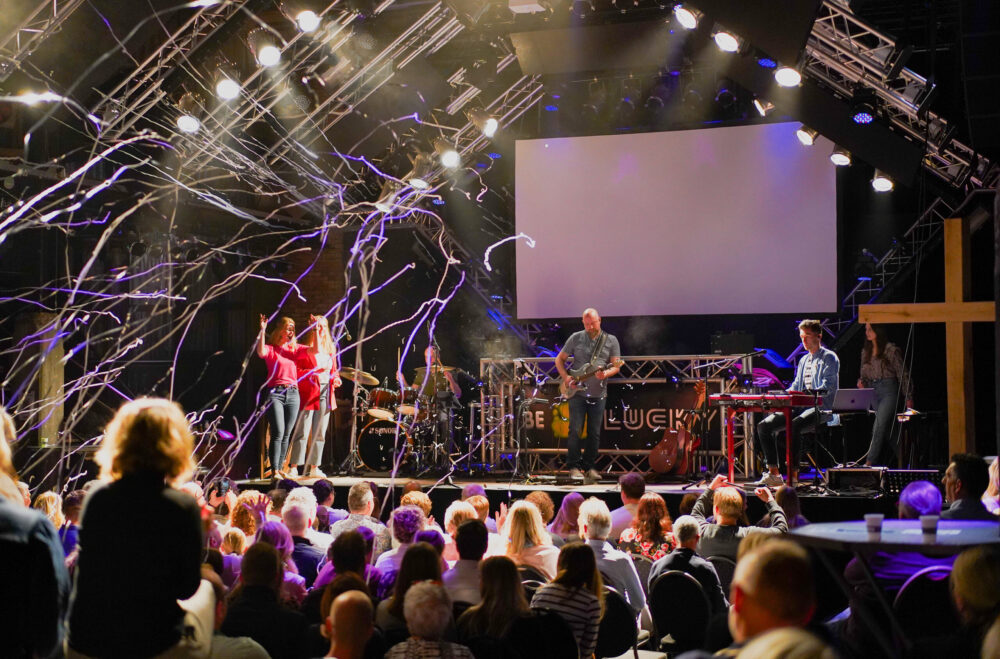 Serpentines dwarrelen boven het podium en de juichende zaal tijdens een dienst van Mozaiek0548