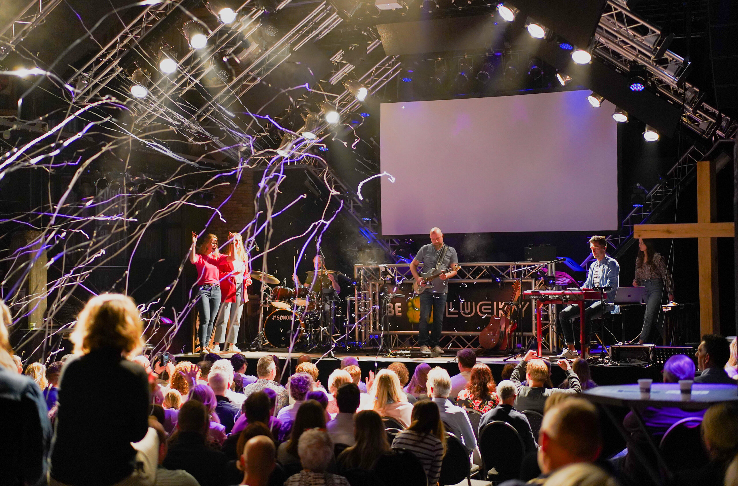 Serpentines dwarrelen boven het podium en de juichende zaal tijdens een dienst van Mozaiek0548