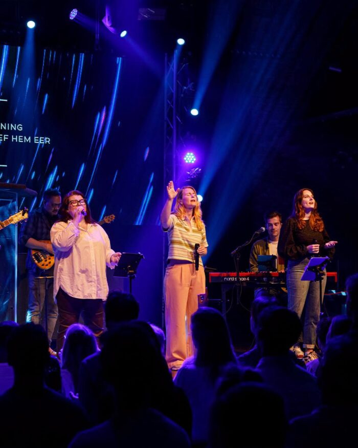 Zangeressen van de worshipband van Mozaiek0548 zingen met opgeheven handen tijdens de dienst