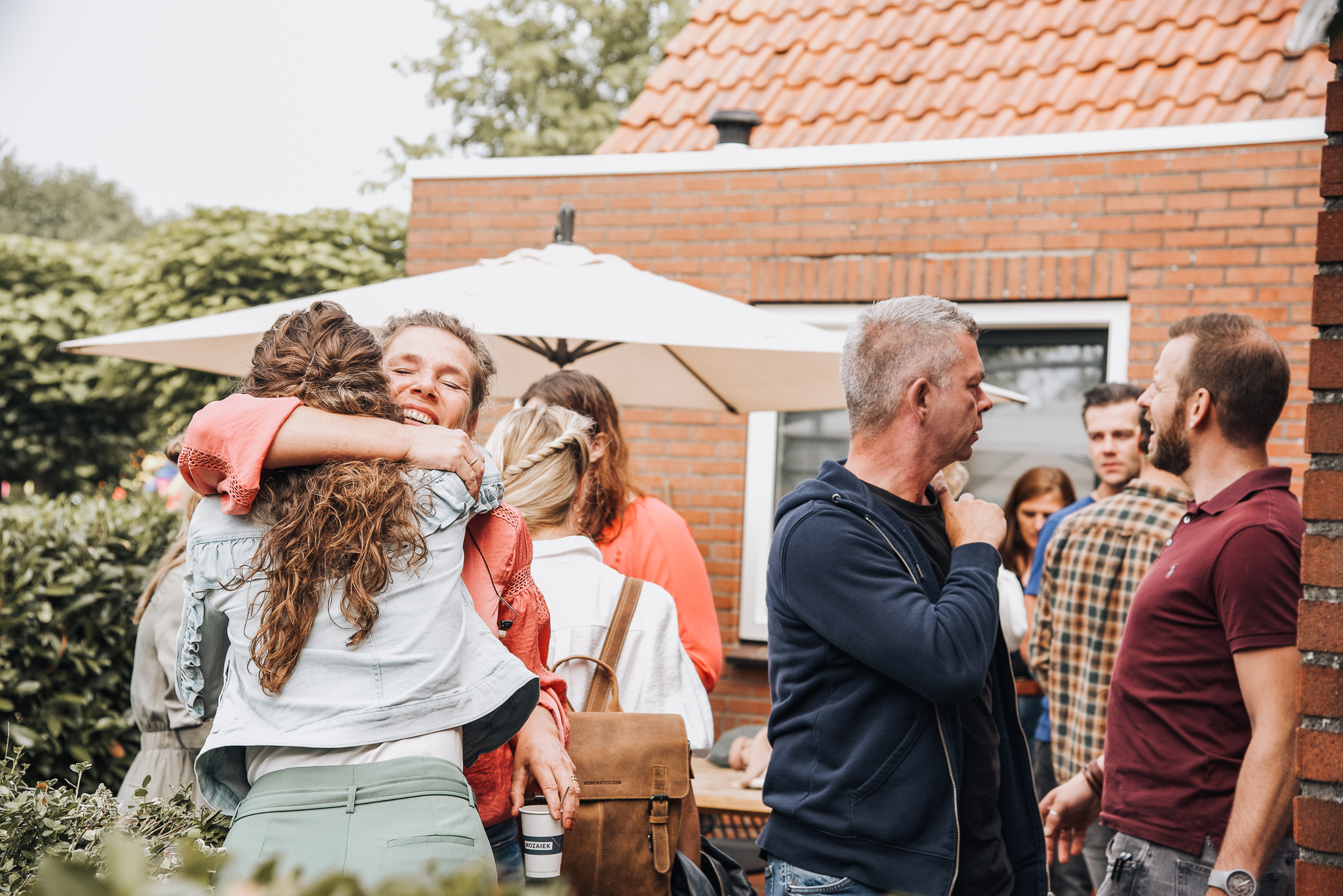 Bezoekers omhelzen elkaar en praten na tijdens de buitendienst van Mozaiek0548