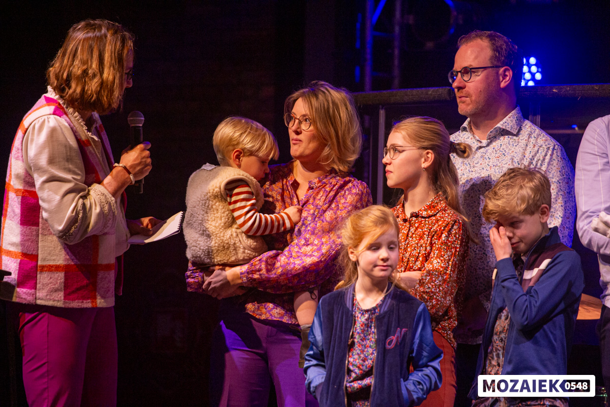 Gezinnen met hun kinderen staan op het podium tijdens een opdraagdienst van Mozaiek0548