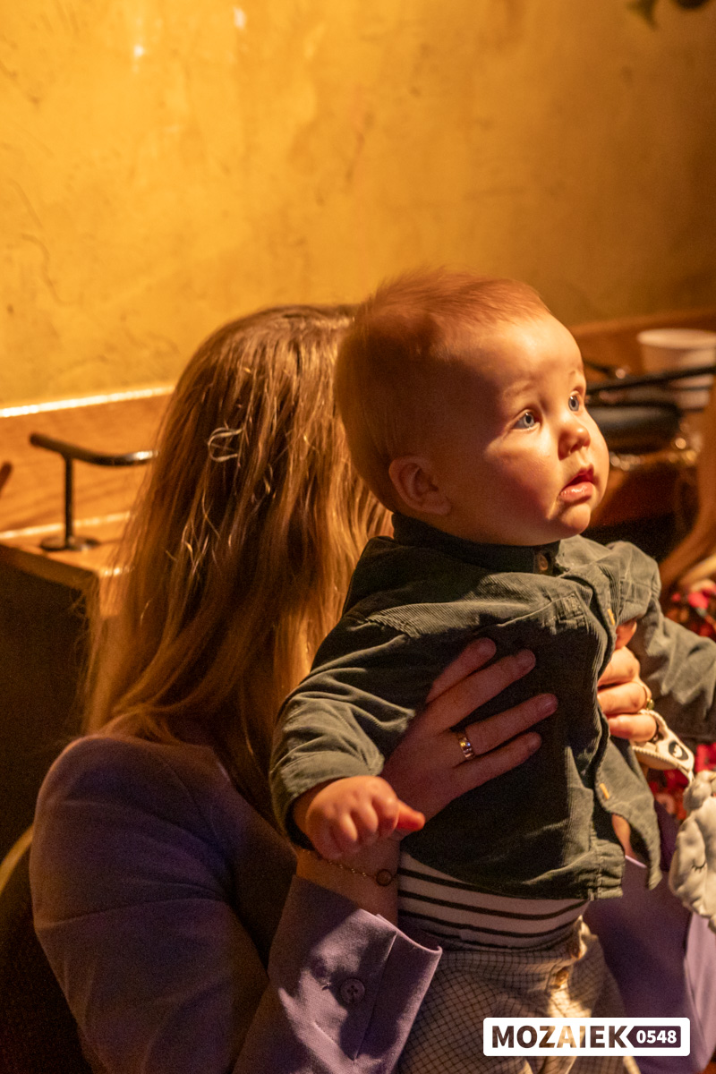 Een baby kijkt rond op de arm van zijn moeder in de zaal tijdens een dienst van Mozaiek0548