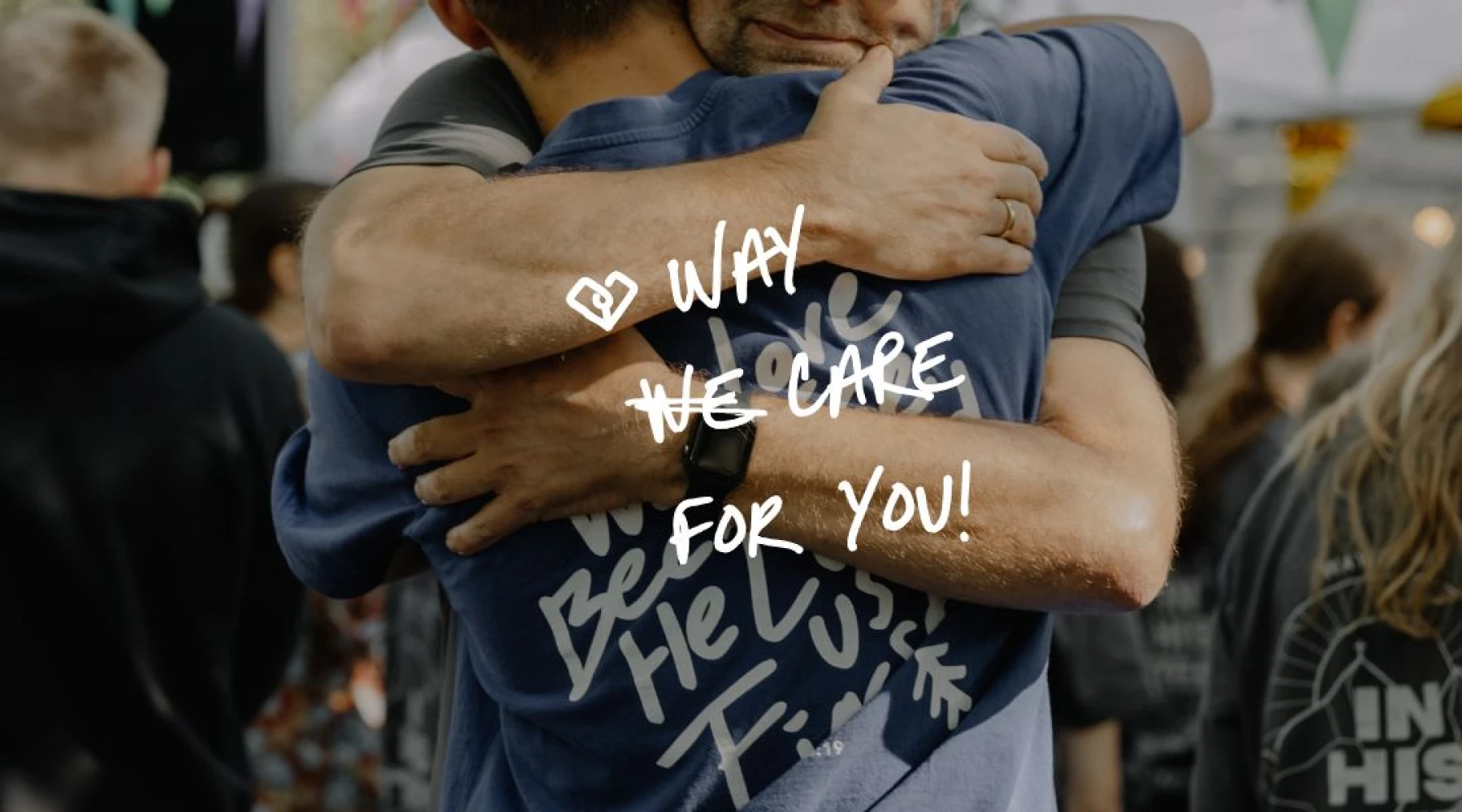 Twee jongeren omhelzen elkaar; op het shirt staat handgeschreven 'WAY we care for you'