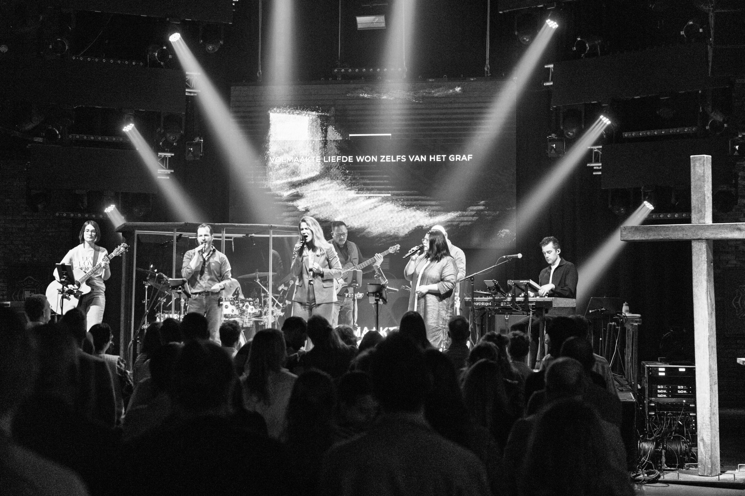 Zwart-witfoto van de worshipband op het podium met bezoekers op de voorgrond