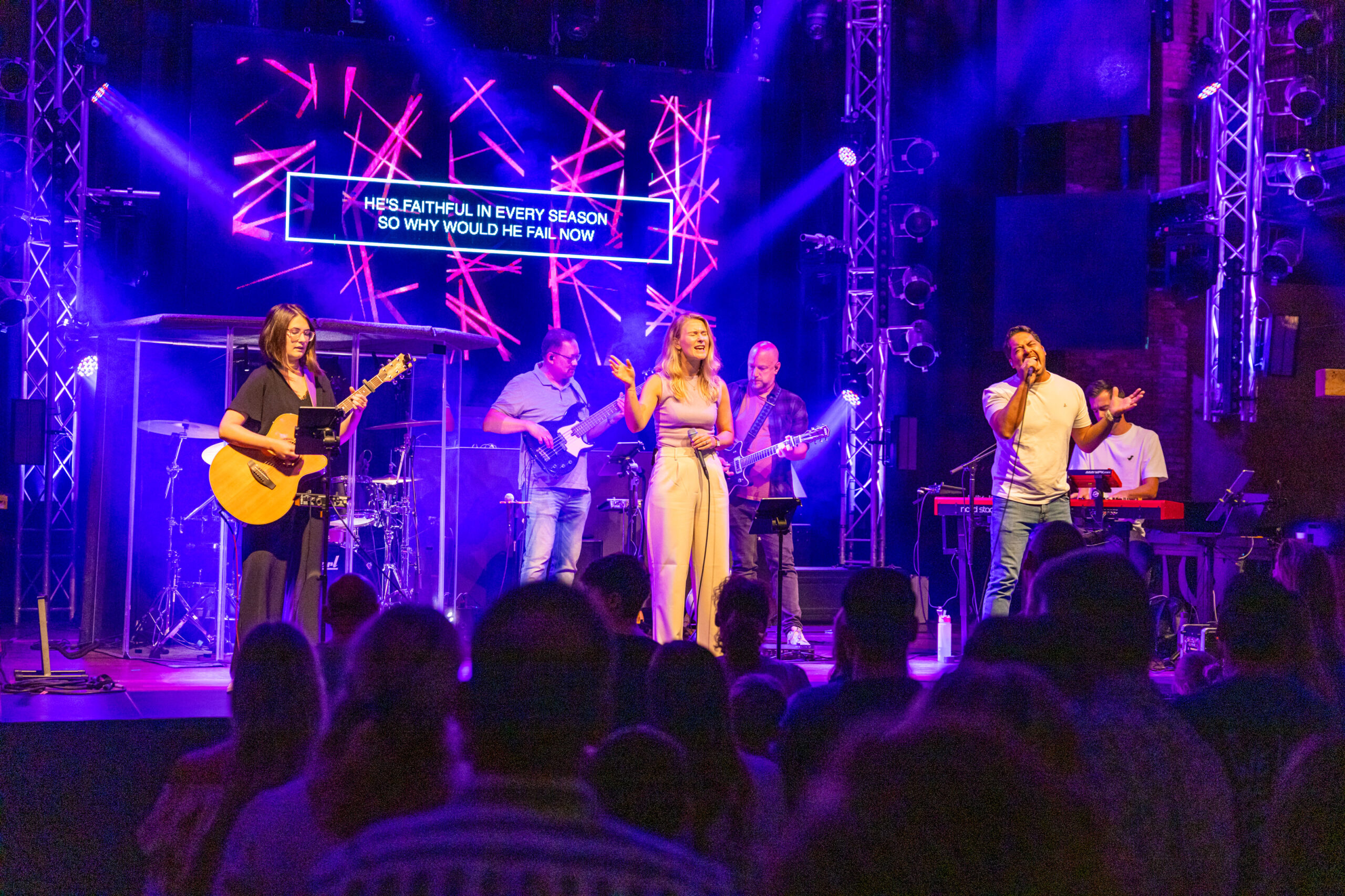 Worshipband met zangeres en zanger op het podium van Mozaiek0548 met paarse lichtshow