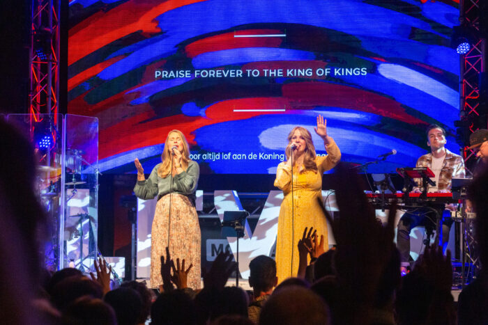 Zangeressen van het worshipteam Mozaiek0548 zingen met opgeheven handen tijdens de dienst